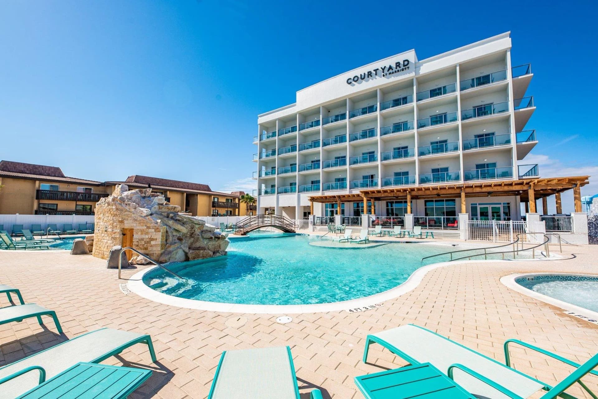 Courtyard by Marriott South Padre Island tower above a lagoon pool with turquoise lounge chairs
