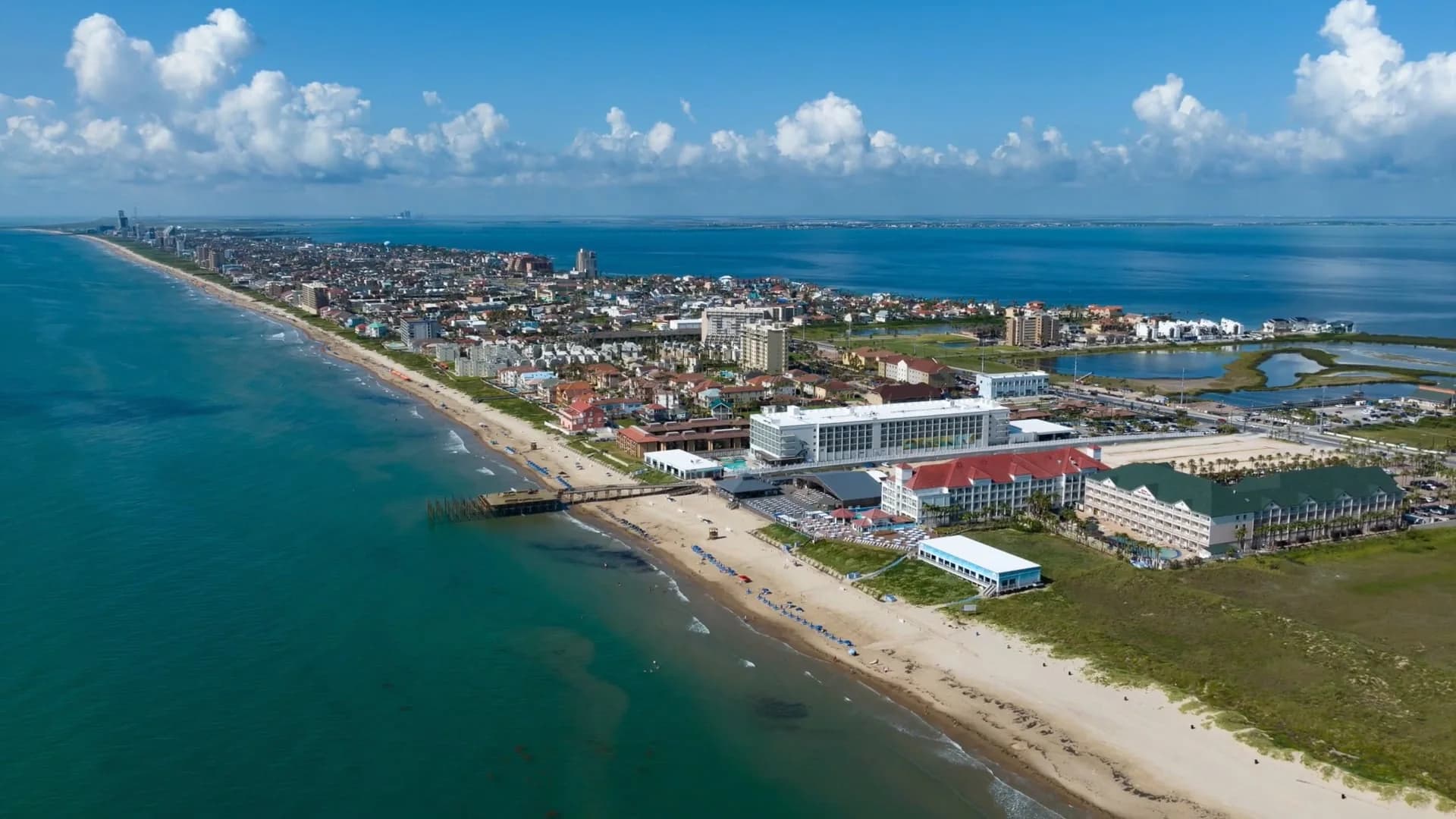 Aerial view of South Padre Island with the beach, a pier and hotels along the shore